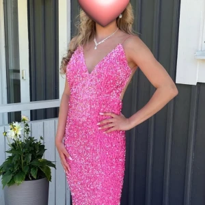 Glittrig rosa långklänning med öppen rygg - Säljer min magiska rosa balklänning med glittriga paljetter över hela klänningen. 🩷Klänningen har smala axelband, v-ringad fram och en helt öppen rygg. Den är figurnära och har en snygg, svepande siluett som verkligen sticker ut. Perfekt för bal eller fest! ENDAST ANDVÄND EN KVÄLL! Så den är i nyskick. 