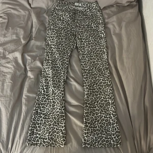 Leopardmönstrade bootcut jeans från Lindex - Säljer ett par bruna och vita jeans från Lindex med leopardmönster. Byxorna har bootcut-ben, klassisk femficksdesign och knappstängning fram. Perfekt för dig som vill sticka ut med ett djuriskt print och cool siluett.