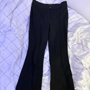 Svarta kostymbyxor från Zara - Snygga svarta kostymbyxor/leggings material  från Zara. Byxorna har en klassisk knappstängning fram och är tillverkade i ett mjukt material som ger en stilren look. Perfekta för dig som gillar en trendig och clean stil.