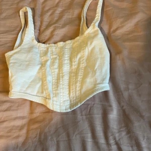Vit korsett-topp  - Säljer en vit korsett-topp storlek XS. Toppen har breda axelband, markerade sömmar framtill och en snygg silvrig dragkedja i ryggen. Materialet är mjukt och i demin tyg  perfekt för att lyfta din outfit med en clean vibe. Ny pris 189