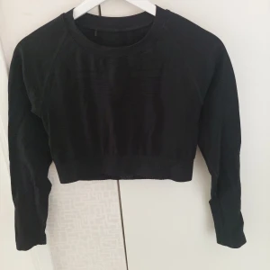 Svart croppad tröja från Gavelo - Svart croppad tröja från Gavelo med rund hals och långa ärmar. Tröjan är tillverkad i stretchigt material med ribbad nederkant och passar perfekt för träning eller chill. Materialet består av 93% polyamid och 7% elastan för en skön och flexibel passform.