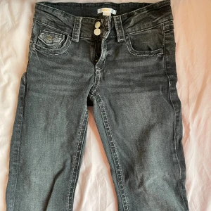 Mörkgrå jeans low waist från Gina Tricot - Snygga mörkgrå jeans från Gina Tricot i storlek 158. Modellen har klassisk femficksdesign, kontrastsömmar och dubbla knappar i midjan. Jeansen har rak passform och är tillverkade i mjukt denimtyg med lätt tvättad look.