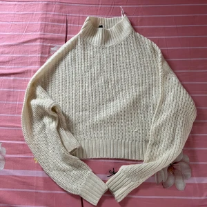 Beige stickad polotröja från H&M - Säljer en beige stickad polotröja med grov struktur och ribbade muddar köpte från H&M. Tröjan har hög krage och långa ärmar, perfekt för kyliga dagar. Enkel och stilren design som är lätt att matcha med olika outfits.