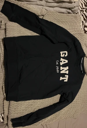 Två stycken marinblåa sweatshirts från GANT - Två marinblåa sweatshirts från GANT. Klassisk rund hals och långa ärmar, tillverkad i mjuk bomull. Perfekt för dig som gillar stilrena och sportiga plagg med tydlig branding.