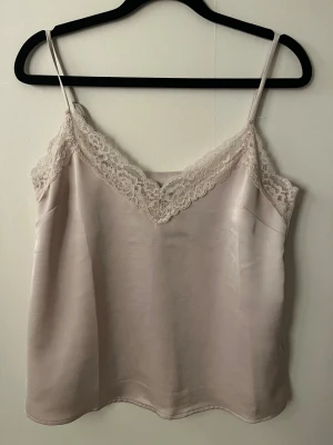 Champagnefärgat linne med spets - Supersöt champagnefärgat linne från Kappah men justerbara band. Säljer då den tyvärr har blivit för liten.