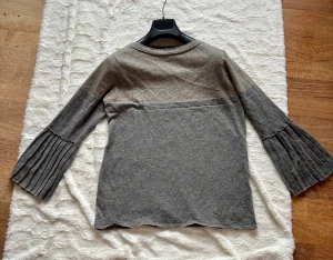 Grå glittrig tröja från Gustav - Supersnygg grå tröja från Gustav med glittrig silverfärgad överdel och breda plisserade ärmar. Mjuk och skön mix av ull, viskos och bomull. Perfekt för dig som vill ha något extra till din look. Rund halsringning och loose passform. Inköpt i den fina butiken i Bromma , nypris över 2500 sek