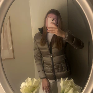 Beige, grå dunjacka från Colmar  - Säljer en grå, beige dunjacka från Colmar  med huva. Den är nästan oanvänd och lång i ärmarna. Jackorna är små i storlek så den motsvarar S.