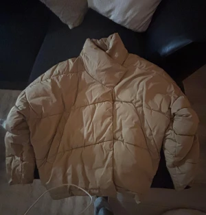 Beige pufferjacka från BikBok M - Jackan är quiltad med hög krage och knäppning framtill. Den har en loose fit och är perfekt för kyligare dagar. Materialet är syntet och jackan är riktigt skön och trendig.