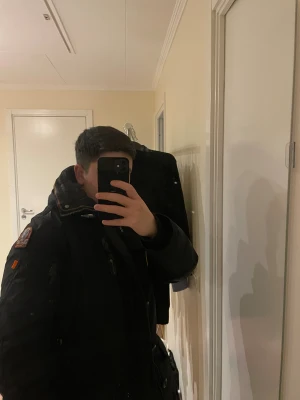 Svart parkajacka med päls från Parajumper - Svart parkajacka i slim fit från Masterpiece Series, med snygg päls på huvan och coola gula detaljer. Jackan har flera fickor, dragkedja och knappar framtill, samt ribbade muddar vid ärmslut. Perfekt för kalla vinterdagar och har en riktigt urban vibe. Använd en halv vinter Köpt för 11 000kr storlek XS Long