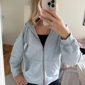 Ljusgrå hoodie från Bikbok med dragkedja - Säljer en ljusblå hoodie från Bikbok i storlek XS. Hoodien har dragkedja framtill, två fickor. Materialet på insidan är fortfarande mjukt. Passformen är normal och ärmarna är långa med ribbade muddar.