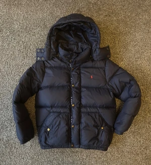 Ralph lauren jacka - Checka in resten av mina jackor!                  Mörkblå Ralph lauren jacka, riktigt snygg och perfekt till vintern. Är i bra skick med några små defekter som visas på bild. Storleken är L ungdomsstorlek, men sitter som xs/xxs herrstorlek. Tveka inte med frågor!