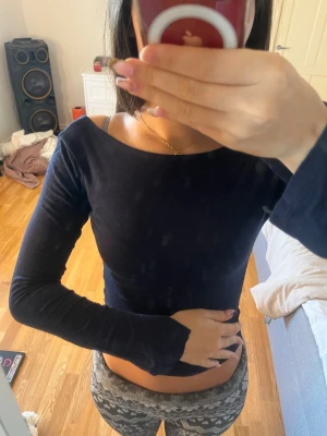 Mörkblå långärmad topp från Missay - Säljer en mörkblå långärmad topp från Missay med öppen rygg. Toppen har en slim passform och är tillverkad i mjukt stretchigt material som sitter snyggt mot kroppen. Perfekt för dig som gillar stilrena och enkla plagg med en twist.