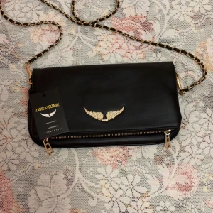 Svart axelväska från Zadig & Voltaire - Snygg svart axelväska från Zadig & Voltaire i skinn med guldfärgade detaljer och kedja. Den är helt oanvänd, i perfekt kvalité och har loggan och taggen kvar. Du får med original förpackning och extra kedjan. För mer bilder skriv och pris kan diskuteras.