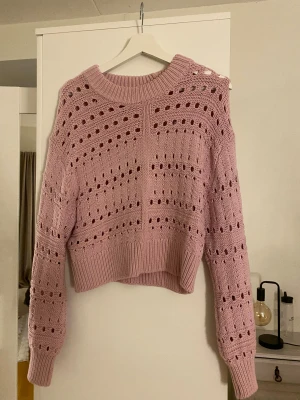 Ljusrosa stickad tröja Gina Tricot - Superfin ljusrosa stickad tröja från Gina Tricot i storlek S. Tröjan har ett snyggt hålmönster, ribbad kant vid hals och nederdel samt långa ärmar. Croppad passform som ger en trendig look. Perfekt att styla med jeans eller kjol. Mycket bra skick