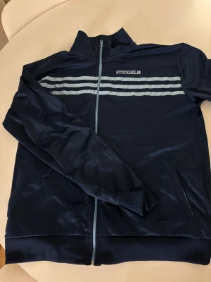 Djurgården stockholm zip - Djurgården stockholm zip tröja riktigt snygg  farsans gamla, såldes för några år sedan vet inte exakt vilket år men riktigt snygg. Den är i storlek XL och helt fel fri.
