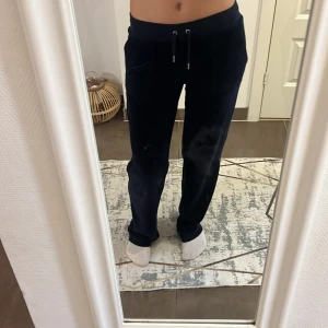 Mörkblå velourbyxor Juicy Couture S - Mörkblå mjukisbyxor från Juicy Couture i velour med snörning i midjan och fickor både fram och bak. Klassisk logga broderad på fickan och silverfärgade detaljer. Perfekta för en chill och trendig look.