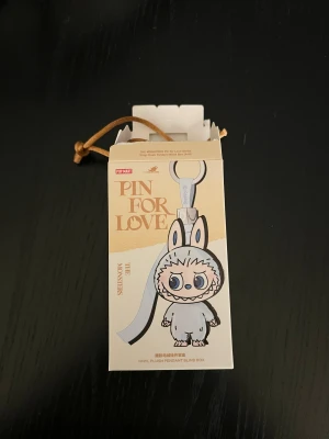 Pop Mart Pin For Love Labubu - Hej! Har 5 st labubu pin for love, bokatäverna som finns är:  F K I  J & ?   Alla är öppnade, men kommer i en påse man kan dra igen, så jag kommer att tejpa igen själva kartongen vid köp. I & med att det är en påse, kan ni vid köp be om att jag bara skickar med en random, så att det blir en överraskning , men ni kan självklart oxå välja bokstav av dessa som finns. Alla är äkta, köpta på Hemmakväll. Kortet till varje medföljer också.   Obs, priset avser en labubu.
