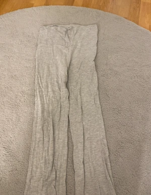 Grå mjukisbyxor från Gina Tricot - Superbekväma grå mjukisbyxor från Gina Tricot i storlek 158/164. Byxorna har hög midja och är tillverkade i mjukt bomullsmaterial. De har ett loose fit med raka, vida ben och är perfekta för chill dagar hemma eller när du vill vara extra comfy.