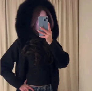 Alessa jacka - Säljer en svart cardigan jacka med fluffig pälsluva. Jackan har dragkedja framtill och är croppad i modellen. Perfekt för dig som vill ha en mysig och snygg look med extra attityd. By condition