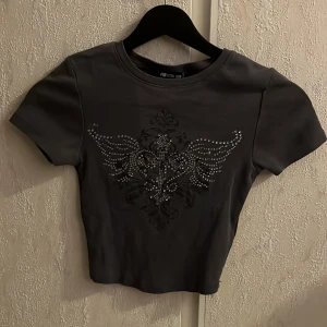 Croppad t-shirt med paljettkors - Croppad t-shirt med paljetter från fb sister. Storlek XXS. Säljer då den är för liten.
