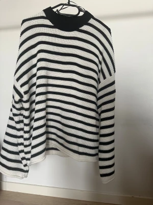 Stickad tröja från Junkyard - Säljer en  stickad tröja med svartvita ränder och rund hals från Junkyard. Tröjan har långärmade, lite loose passform och är gjord i ett mjukt stickat material.   Obs: Alla plagg säljs endast fram till 28/12 