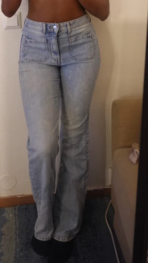 Ljusblå high waist jeans med raka ben - Säljer ett par ljusblå jeans med hög midja och raka ben , jag är 170cm lång. . Jeansen har klassiska fem fickor, synlig knapp och dragkedja framtill. Materialet är jeans och passformen är normal med en straight siluett. Perfekt för dig som gillar en clean och enkel look.