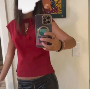 Röd blus perfekt för julen - Snygg röd blus med korta ärmar och en liten rosett framtill vid halsringningen. Perfekt nu till julen eller bara att ha vardagligt. Jättefin, passar med allt!