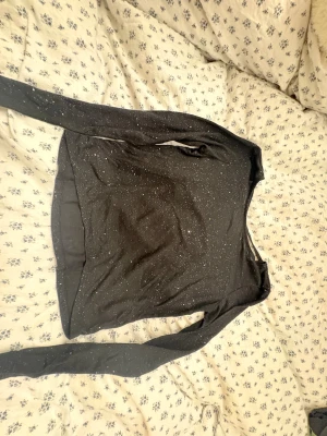 Svart glittrig långärmad tröja H&M - Svart långärmad tröja från H&M med glittriga detaljer som ger ett snyggt skimmer. Tröjan har en enkel, klassisk passform och är perfekt för dig som gillar lite extra bling i vardagen. Materialet är mjukt och bekvämt mot huden. Med en liten öppen rygg.