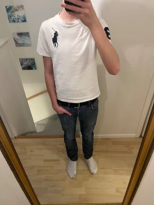 Vit Polo Ralph Lauren t-shirt med tryck - Vit t-shirt från Polo Ralph Lauren med klassisk mörkblå polospelare broderad på bröstet och en stor mörkblå siffra 3 på ena ärmen. Rund hals och korta ärmar, tillverkad i mjuk bomull. Snygg och stilren design som funkar till jeans eller shorts.