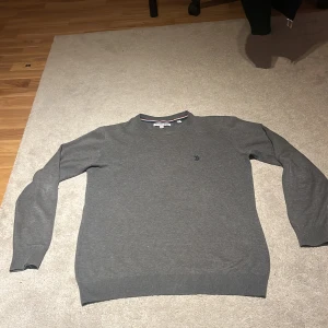 Mörkgrå tröja U.S. Polo Assn. - Mörkgrå tröja från U.S. Polo Assn. med rund halsringning och diskret broderad logga på bröstet. Tröjan är långärmad och har ribbade muddar vid ärmslut och nederkant. Perfekt för dig som gillar en clean och klassisk stil.