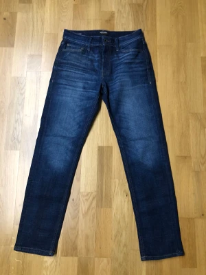 Jack & Jones mörkblå jeans 29/32 - Snygga mörkblå jeans från Jack & Jones i klassisk straight fit. Jeansen har fem fickor, kontrastsömmar och en läderpatch med logga bak. Materialet är slitstarkt denim i bomull och passformen är normal. Perfekta för dig som gillar stilrena och tidlösa jeans. Dessa jeansen är helt nya aldrig använda bara testade på en gång, priset är såklart diskuterbart. 