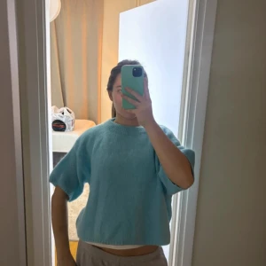 Ljusblå stickad kortärmad tröja - En stickad kortärmad tshirt i super snygg ljusblå/turkos färg. Köpt i Amsterdam, gjord av mohair blandning 