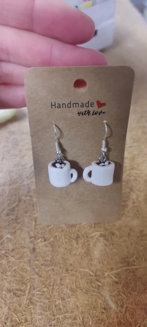 Varm choklad med marshmallows öronhängen - Unika handgjorda örhängen, skapade med polymerlera. Formade som små vita koppar med varm choklad på toppen. Perfekt för dig som älskar varm choklad och vill ha något annorlunda och personligt i din stil. Krokarna är i silverfärg och kopparna är i vit nyans.