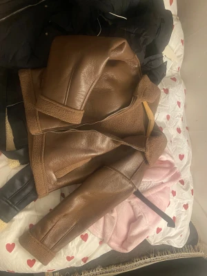 Brun teddyjacka med dragkedja - Säljer en brun teddyjacka med mjukt foder och detaljer i samma färg. Jackan har dragkedja framtill, bred krage och muddar i teddy. Perfekt för kalla dagar och ger en cool look med sitt klassiska snitt.