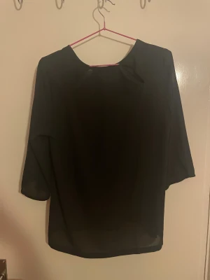 Svart blus med trekvartsärm - En svart blus med rund halsringning och trekvartsärmar. Tunt och lätt material som ger en luftig känsla. Perfekt att styla med jeans eller kjol för en enkel och stilren look.