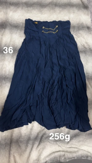 Marinblå klänning med kedjedetalj - Snygg marinblå klänning med crinklad effekt och coola kedjedetaljer framtill. Klänning har en avslappnad passform och är perfekt för dig som gillar boho-vibe och vill sticka ut lite extra. Lätt och luftig, passar till många olika stilar.🌸Fint använt skick. Storlek 36