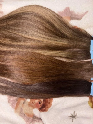 Hårförlängning tape i människohår - 60 bitar tejp-extensions i 16–20 inch (45–50 cm), totalt ca 150g i äkta människohår. Majoriteten är slingade, de hel bruna är i två olika toner då jag blekt ena halvan med svag blekning, men kvaliteten kvarstår densamma. Du kan bleka eller färga håret till den färgen du önskar då det är människohår. 3 tapes är 14inch pågrund av att jag klippt dom för att få layers effekt, resterande 57 bitar tejp är mellan 18-20inches. Originalpris 2150 inklusive tull. Har satt på tejp, så de redo att användas.