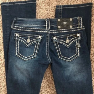 Mörkblå Miss Me bootcut jeans - Snygga mörkblå jeans från Miss Me med bootcut passform och kontrasterande vita sömmar. Midjemått 35-36 cm innerbenslängd 85 cm