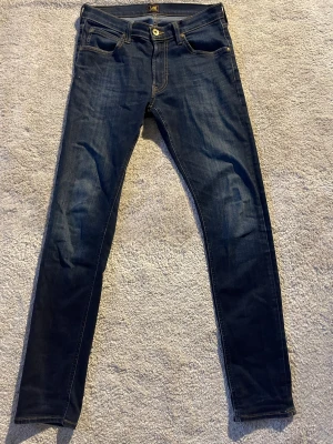 Mörkblå Luke jeans från Lee W29 L32 - Snygga mörkblå Luke jeans från Lee i Slimfit passform med klassisk femficksdesign och gul kontrastsöm. Jeansen har raka ben och är tillverkade i mjukt denimtyg. Inga defekter alls. Hör av dig om du undrar något😁