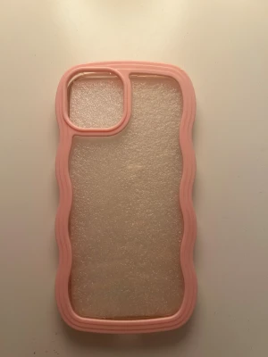 Rosa vågigt mobilskal för iPhone 14 - Rosa vågigt mobilskal för iPhone 14. Se den andra bilden för ytterst liten defekt längst upp på skalets högra hörn. 