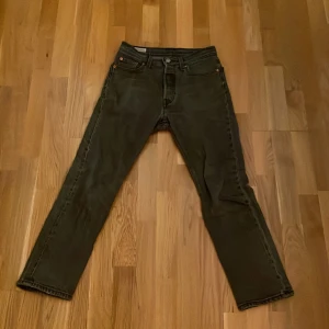 Svarta jeans från Levi's - Klassiska svarta Levi's 501 jeans med rak passform. De har en knappgylf och fem fickor. Perfekta för en stilren look. Storlek W25 L26