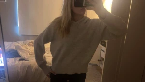 Ljusgrå hoodie med huva och snörning - Mysig ljusgrå hoodie med huva och snörning i halsen. Tröjan har en loose passform och är långärmad, perfekt för chill dagar. Materialet känns mjukt och skönt mot huden, och färgen är enkel att matcha med allt. Snygg basic som funkar året runt.