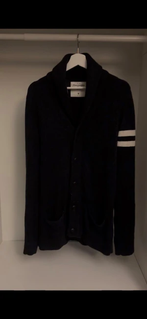 Cardigan från A&F - As fet svart cardigan från Abercrombie & Fitch i storlek M. Riktigt bra för kallare dagar eftersom den är stickad. Riktigt snygg design och riktigt bra skick! Om det finns frågor är det bara att fråga på!