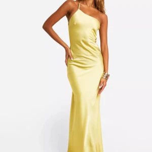 Gul satinklänning med öppen rygg  - Säljer en gul satinklänning med smala axelband och en öppen rygg. Jag köpte den för att använda på min bal men den var för stor för mig. Slut i lager på hemsidan.