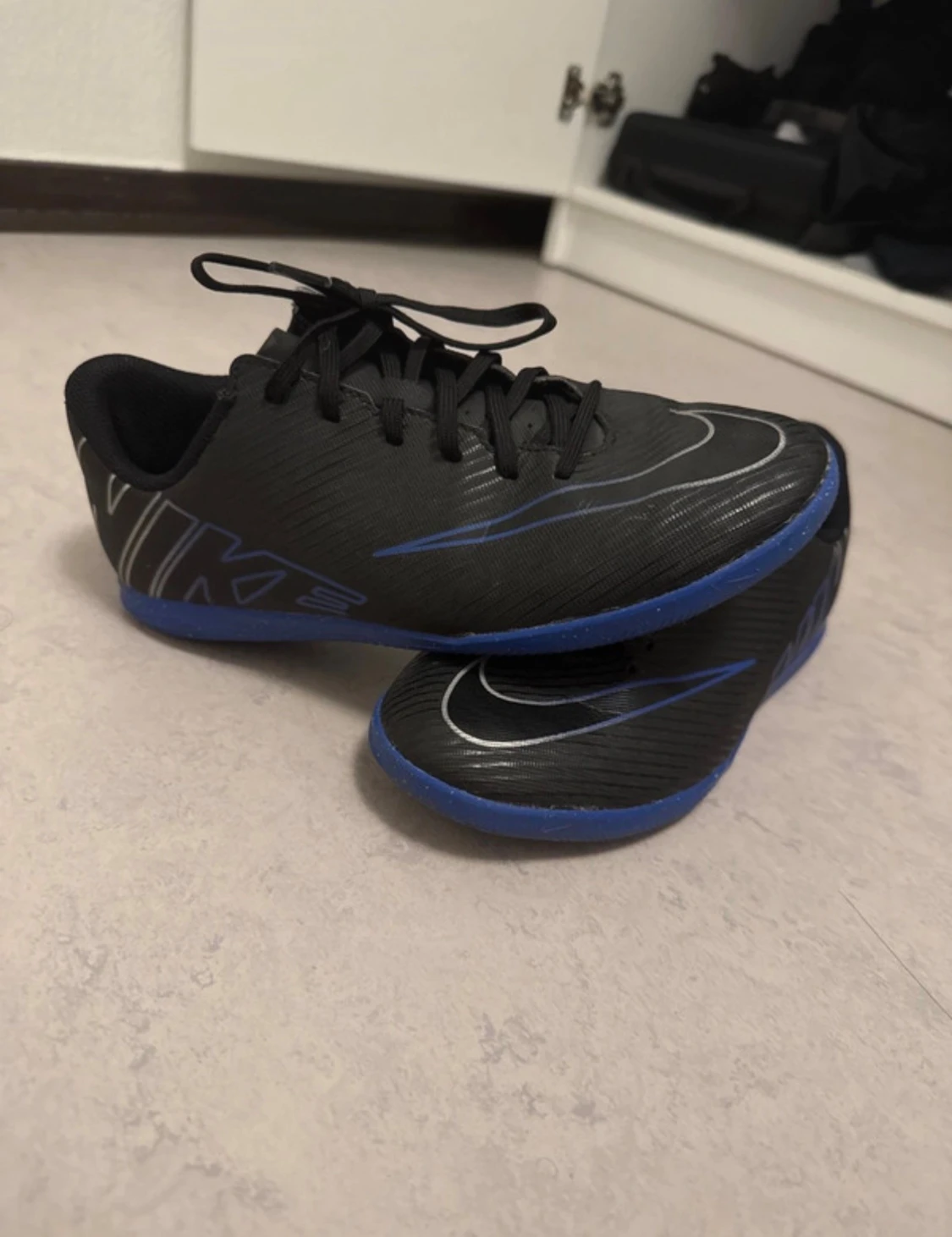 Svarta Nike fotbollsskor med blå sula