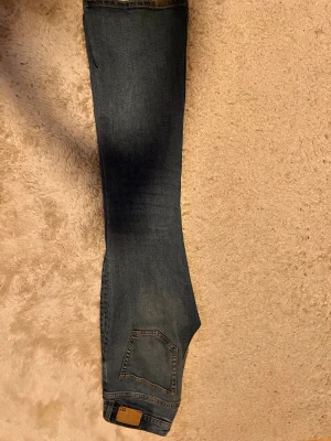 Blå bootcut jeans från lager 157 - Snygga blå jeans från lager 157 med klassisk bootcut-passform. Jeansen har fem fickor, normal midja och lätt slitning på låren för en cool look. Tillverkade i mjukt denimtyg som sitter skönt och ger en avslappnad vibe.