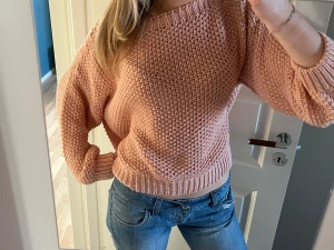 Ljusrosa stickad offshoulder tröja - Supermysig ljusrosa stickad tröja med grov struktur och bred ribbad kant vid hals, ärmslut och nederkant. Snygg offshoulder-passning och lite loose fit, perfekt att matcha med jeans. Tröjan har långa ärmar och är riktigt skön att bära.