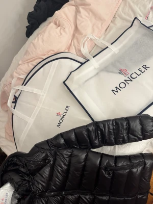 Svart Moncler pufferjacka - Svart pufferjacka från Moncler med glansig finish, huva och dragkedja framtill. Det är modellen bady. Nypris 10000 SEK