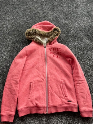 Rosa teddyjacka med päls från O'Neill - Tröjan är väldigt skön och värmande, men säljs då den är lite för tight i ärmen för min smak. Använd endast 1-2 gånger och är i väldigt bra skick. Passar som en s-xs. 