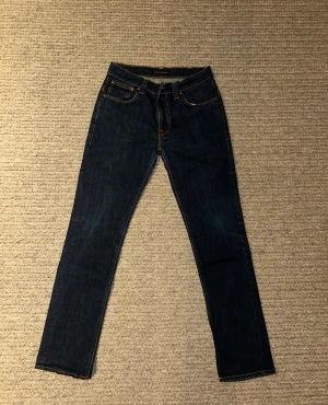 Mörkblå Nudie jeans - Snygga mörkblå jeans från Nudie i modell thinn Finn. Modellen har rak passform och är tillverkad i slitstarkt jeanstyg. Perfekt för dig som gillar stilrena och tidlösa jeans.